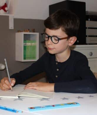 Image d'un enfant en train d’écrire à son bureau dans sa chambre.