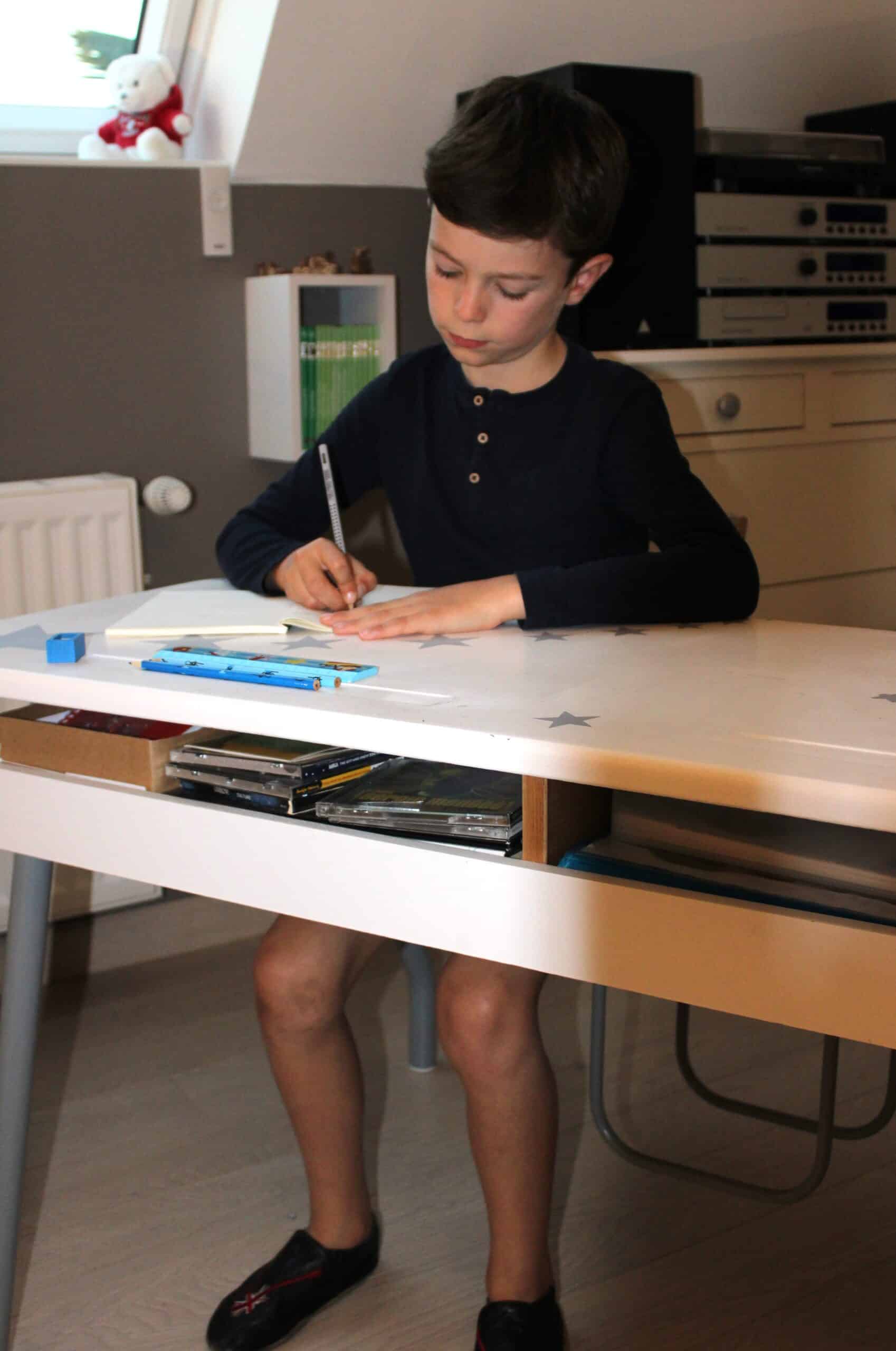 Un enfant qui écrit avec une bonne posture et une bonne tenue de crayon